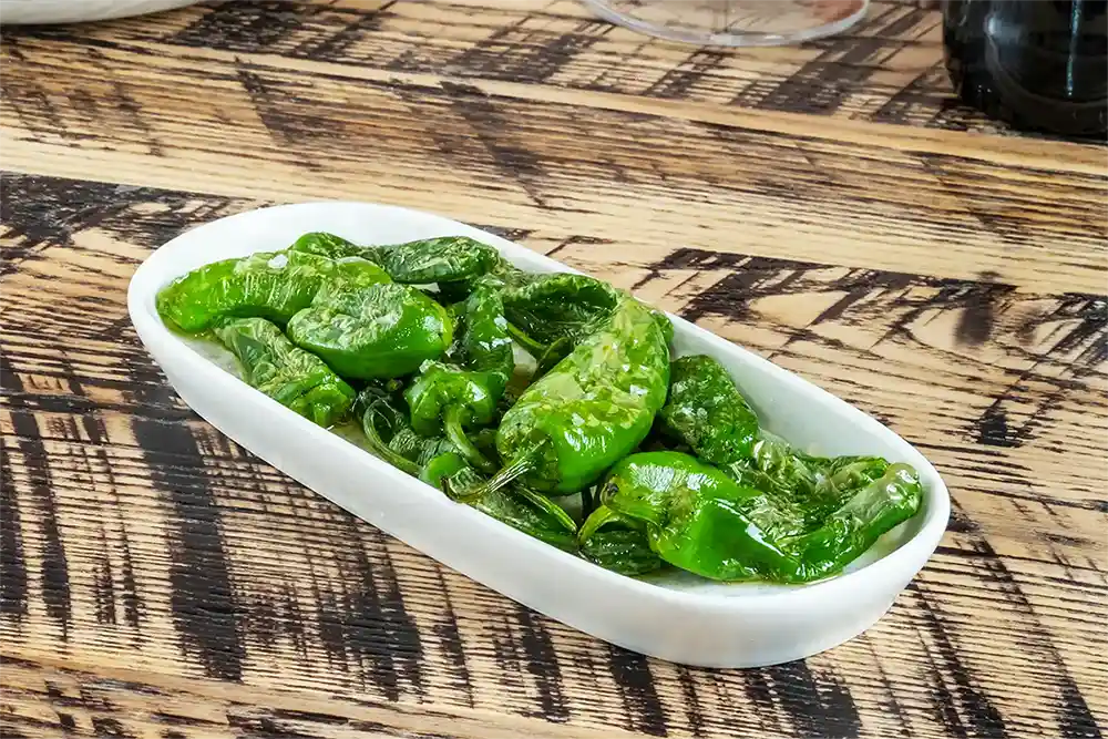 Discover a taste of Spain at our Tapas Restaurant in Manchester, where the classic Padrón peppers are served blistered and sprinkled with sea salt, offering a simple yet irresistible dish that promises a delightful gastronomic surprise with each bite. Perfect for sharing, these succulent green gems are a staple for any tapas lover and a must-try on our menu.






